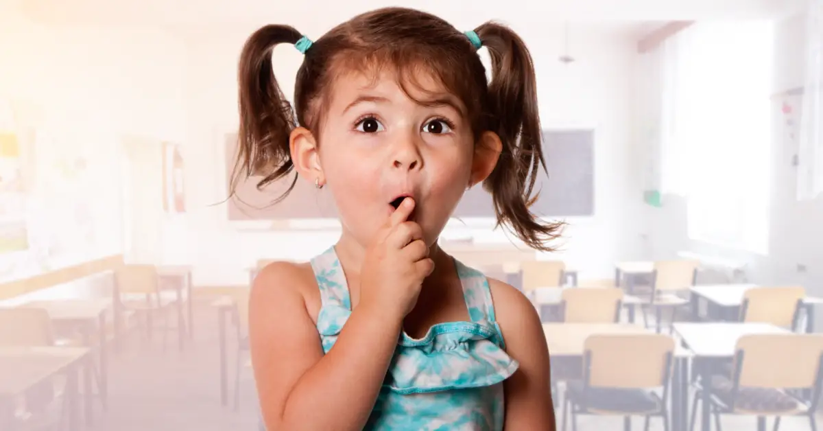 Toddler girl with pigtails in front of a classroom.