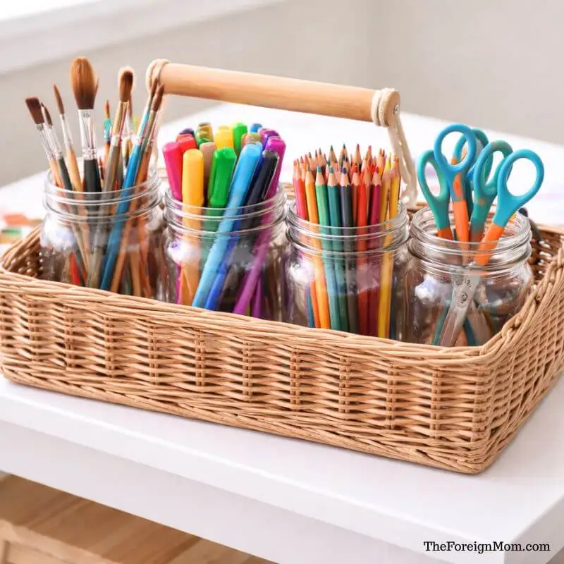 Mason jars in an art caddy organizing kids’ paint brushes, markers, colored pencils, and scissors for easy access.