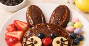 Chocolate bunny pancakes decorated with fruit and a light maple syrup drizzle, a cute Easter breakfast idea for kids.