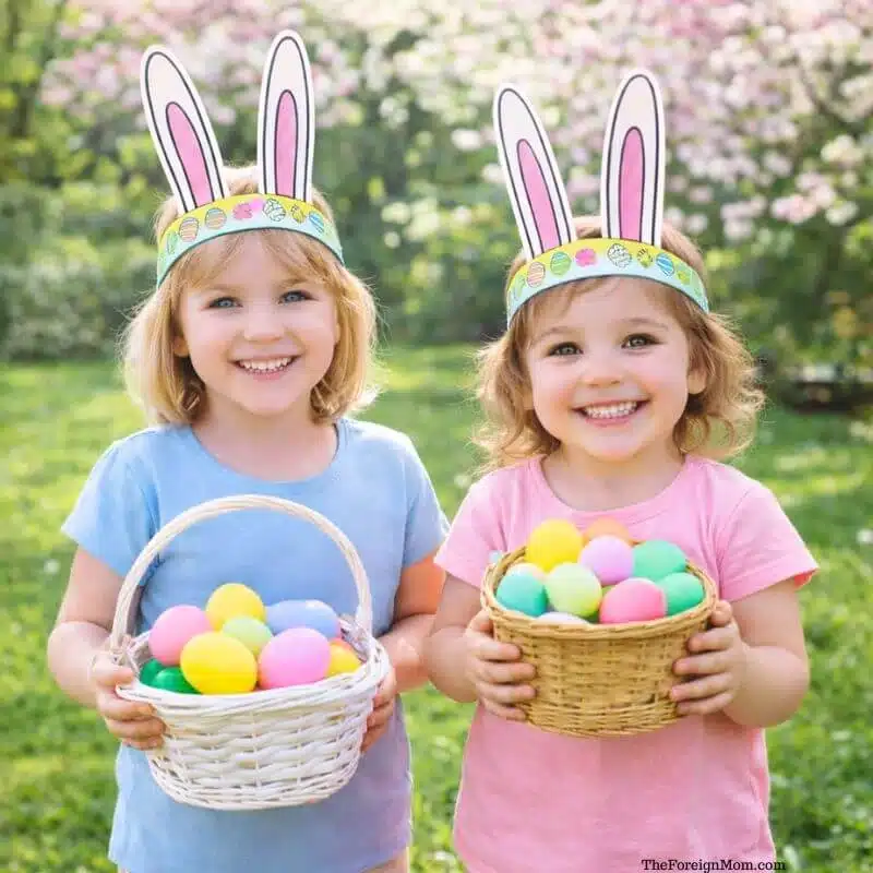 Two girls wearing printable Easter bunny ears headbands holding baskets of colorful eggs during an Easter egg hunt outside in spring garden.