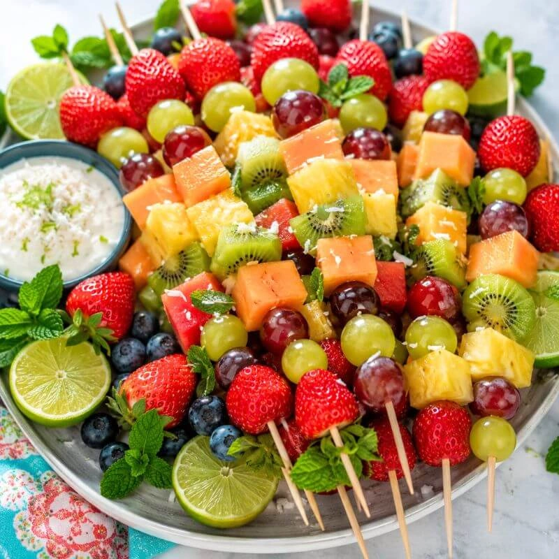 Colorful fruit kabobs made with strawberries, grapes, kiwi, melon, and pineapple served with a creamy fruit dip.
