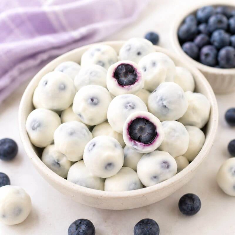 Frozen blueberries coated in Greek yogurt served in a bowl.