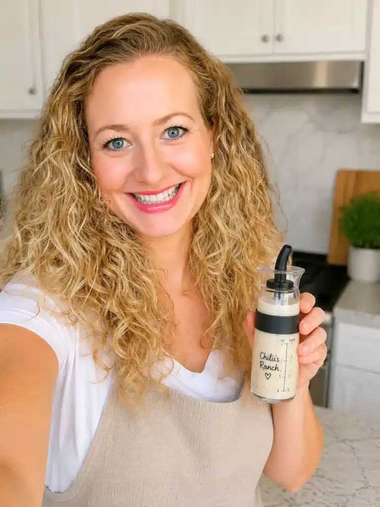 Elisabeth holding a small shaker bottle filled with homemade Chili’s ranch dressing.
