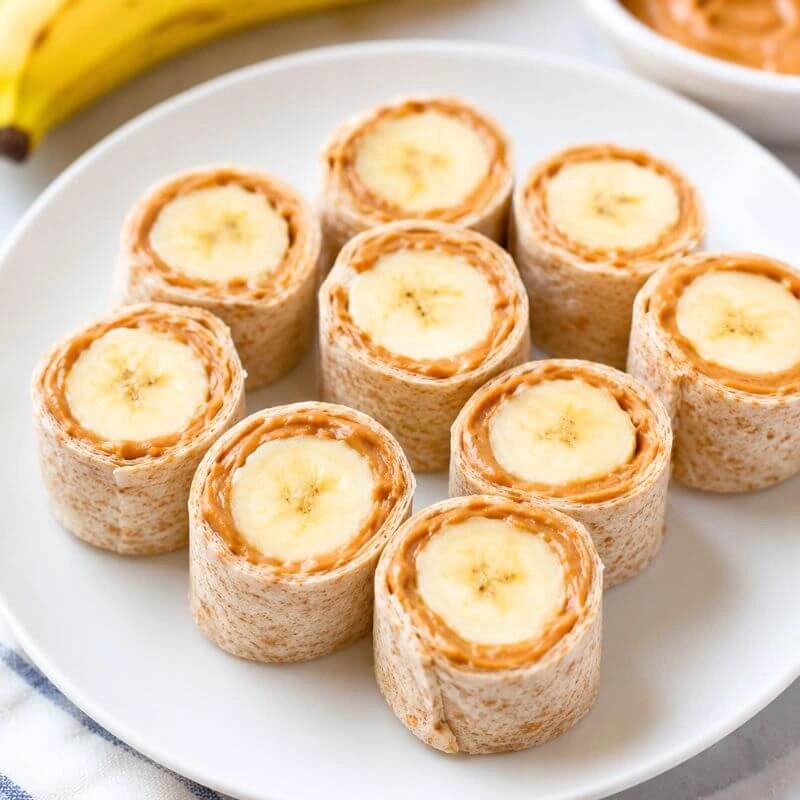 Peanut butter banana sushi rolls made with a whole wheat tortilla, peanut butter, and sliced banana.