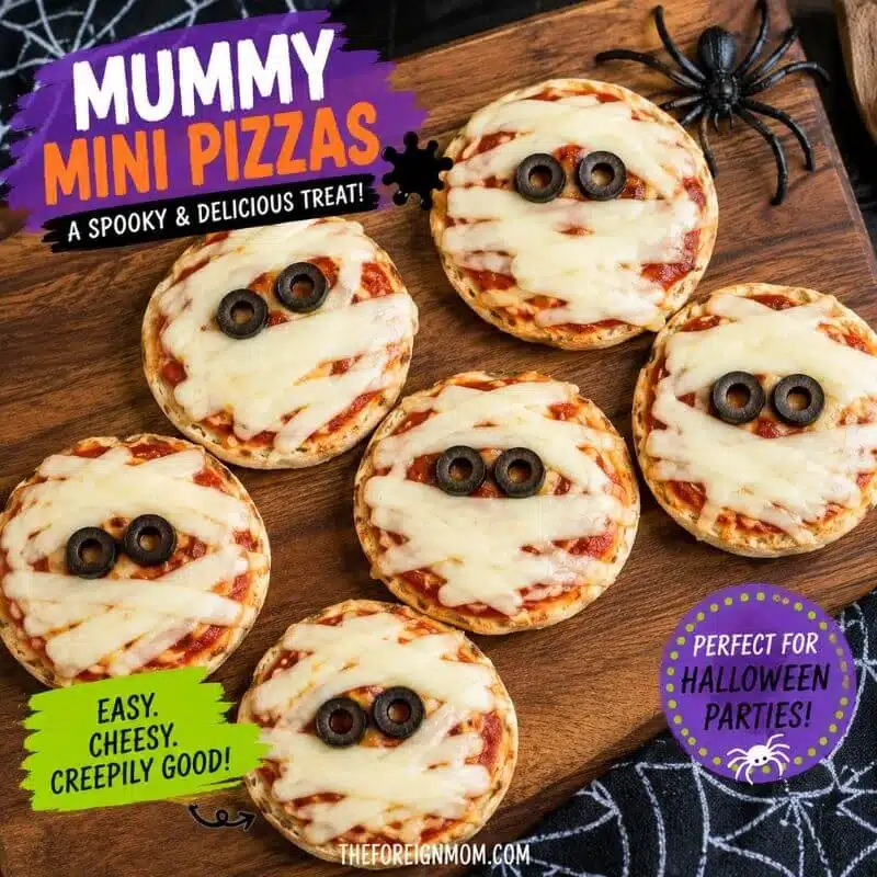 Mummy mini pizzas made with pizza sauce, mozzarella cheese strips, and black olive eyes for a fun Halloween snack for kids.