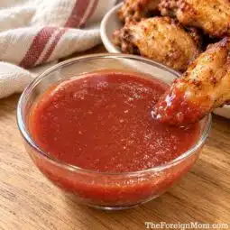 Chicken wing dipped into a glass bowl of homemade Country Sweet sauce.