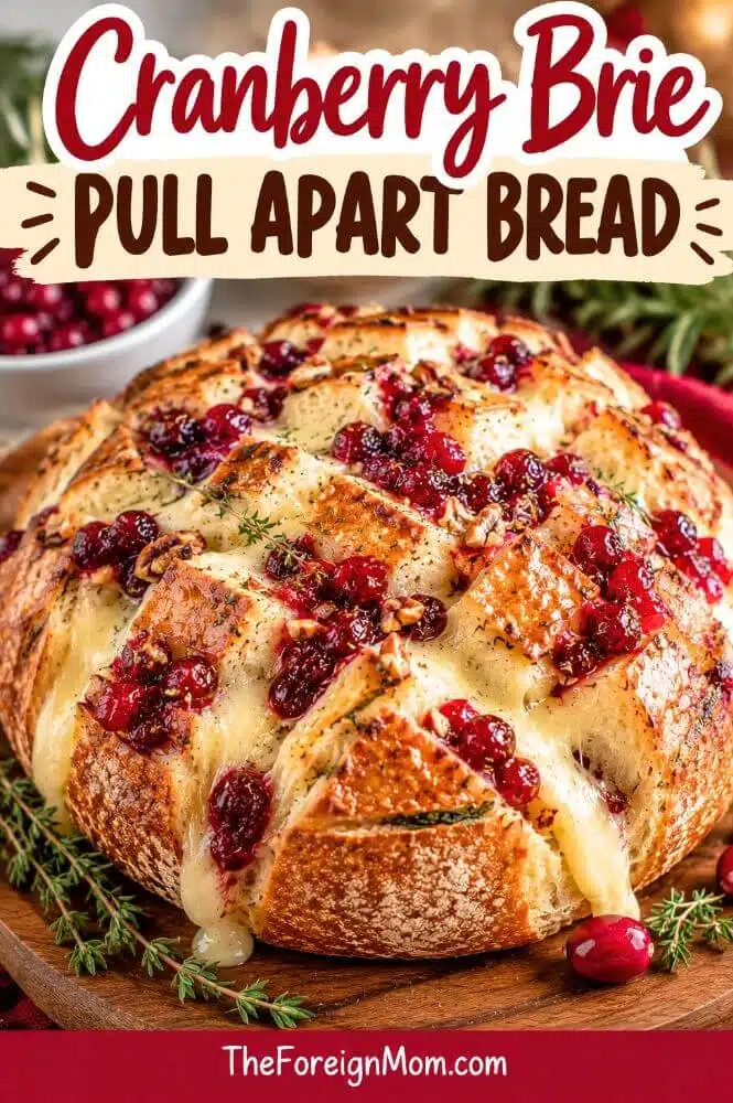 Round cranberry brie pull apart bread filled with creamy melted brie cheese and cranberry sauce, topped with fresh herbs.