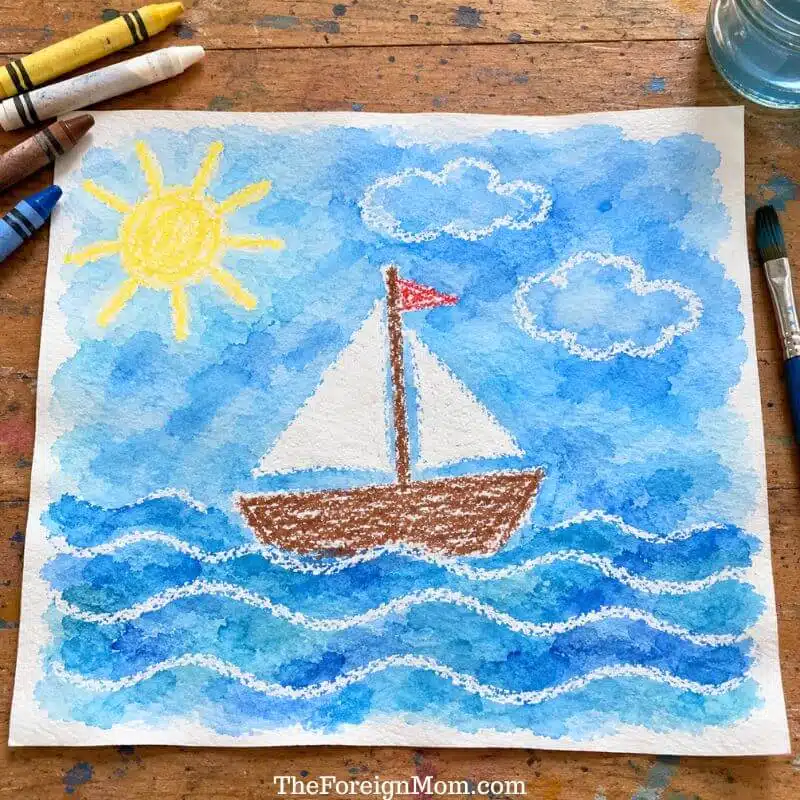 Crayon sailing ship, clouds, sun, and waves showing through a blue watercolor wash.