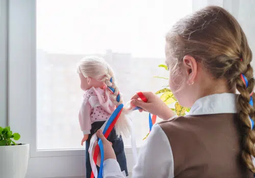Girl with a single braid making dolls hair.