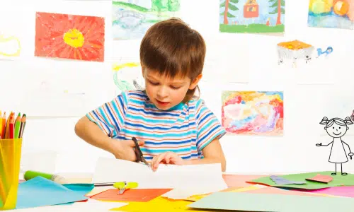 Boy cutting white paper with scissors.