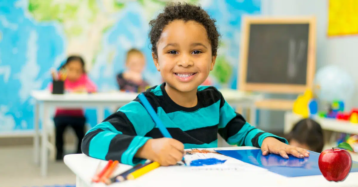 Boy sitting on desk with world map in the background.