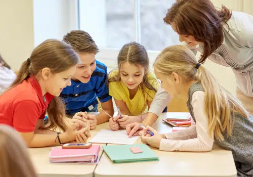 Kids working together on a worksheet smiling.